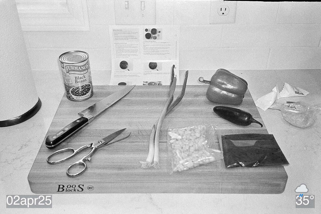 Black and white film photo of cutting board with various items on it