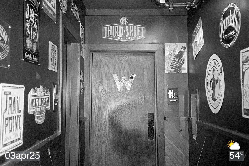 Black and white photo of hallway leading to restrooms at a local restaurant
